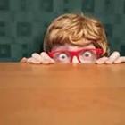 Junge mit roter Brille hinter Tabelle verstecken