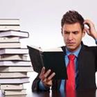 Ein Mann in einem Anzug ein Buch lesen kratzte sich am Kopf neben einem Stapel Bücher
