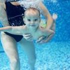 Ein Kind, das Schwimmen mit jemand ihnen halten